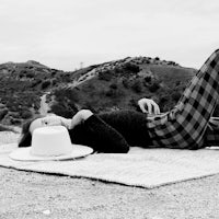 a woman laying on a blanket with a hat on her head